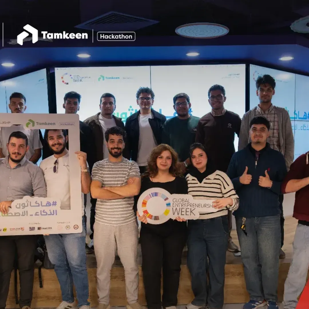 Group photo of AI Hackathon participants at Makers of Baghdad, some holding event photo frames