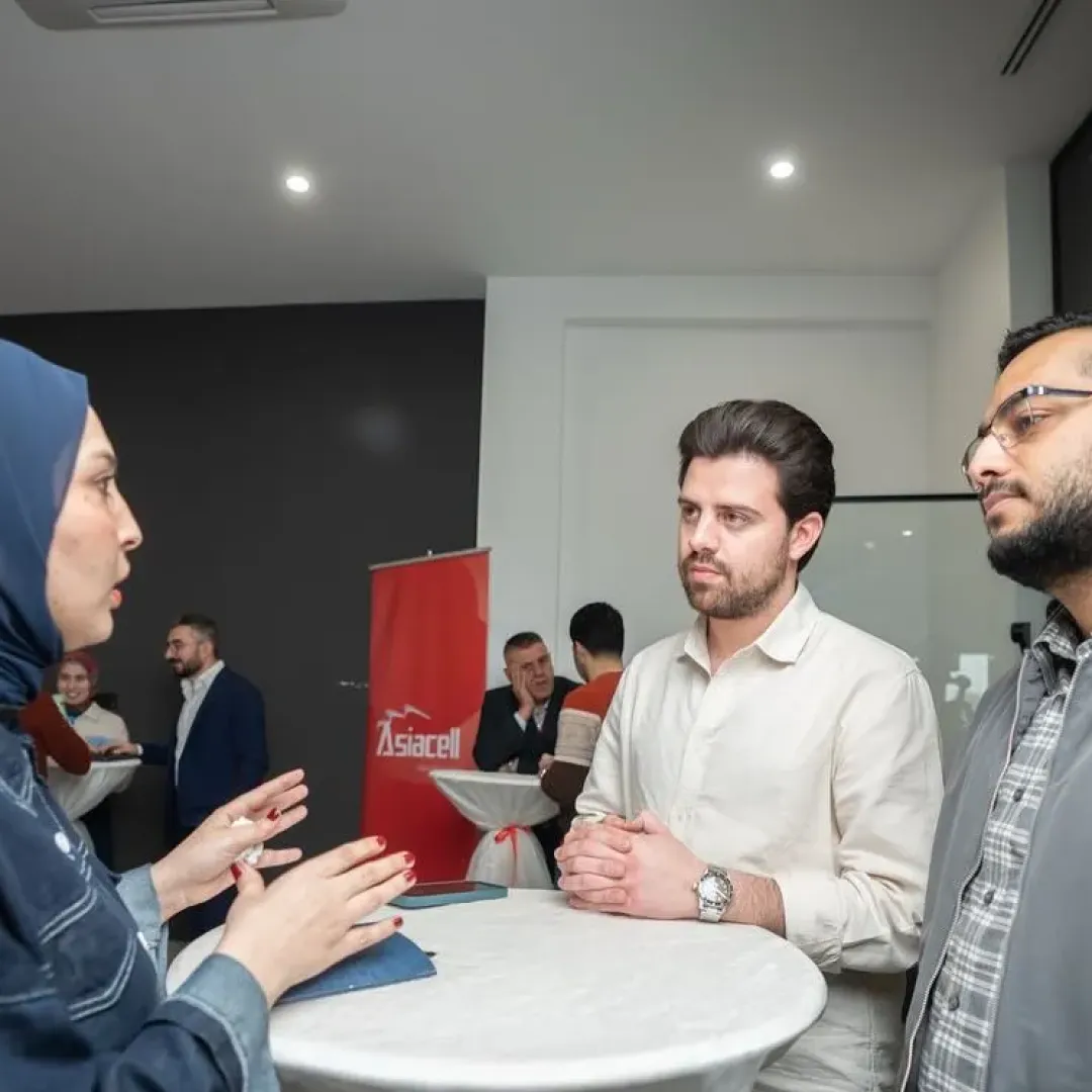 A participant talks with two guests at a table during Coffee Roulette at Qaf Lab