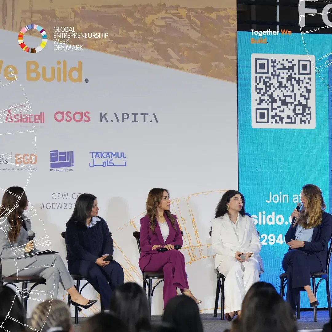 A panel of women speakers on stage at the Women Entrepreneurs Forum Iraq 2025, with the audience in the foreground