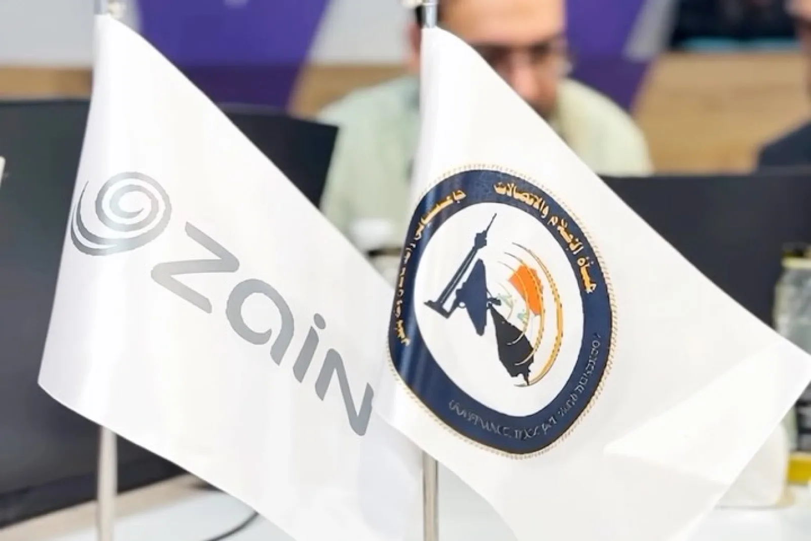 علما زين العراق وهيئة الإعلام والاتصالات على مكتب في قاعة التدريب